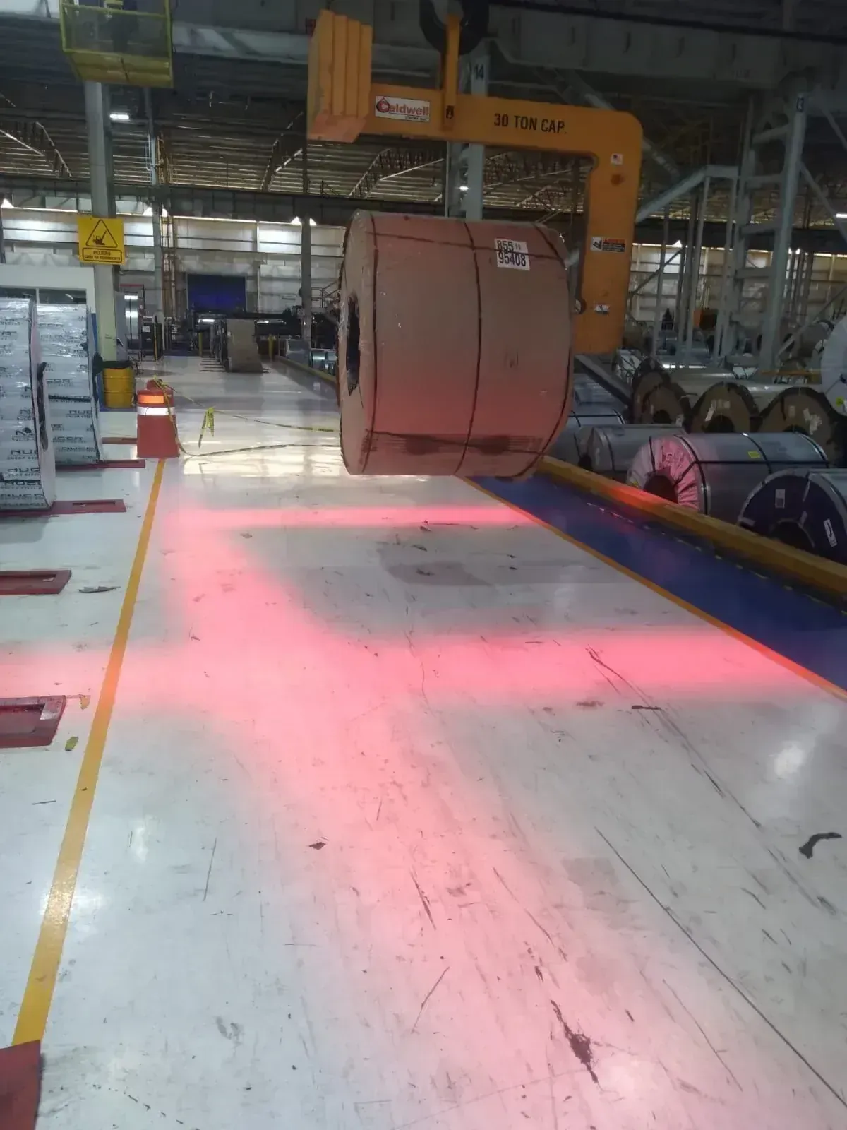 Proyección lineal roja que delimita el área de tránsito junto a bobinas de acero